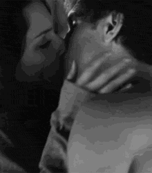 a black and white photo of a man and woman kissing each other .