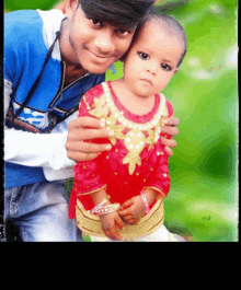 a man in a blue shirt holds a little girl in a red and gold dress