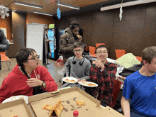 a group of young men eating pizza in front of a white board that says first timer