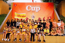 a group of young people posing for a picture in front of a marie curie cup banner