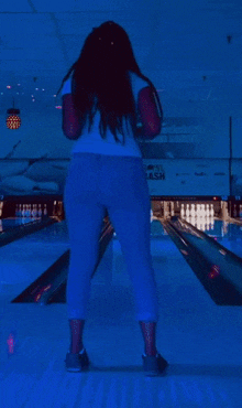 a woman is standing on a bowling alley in front of a sign that says ' bowling alley ' on it