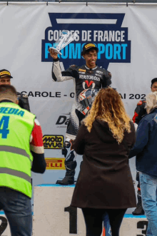 a man holding a trophy in front of a banner that says " cours de france "