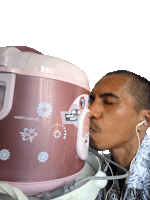 a man wearing ear buds kisses a pink rice cooker that says ' motif nusantara ' on it