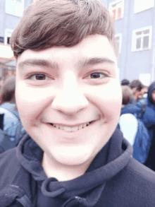 a young man wearing a black jacket with the letter c on it smiles for the camera