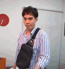 a man wearing a striped shirt is carrying a black purse