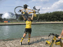 a woman in a yellow shirt holds up a bike