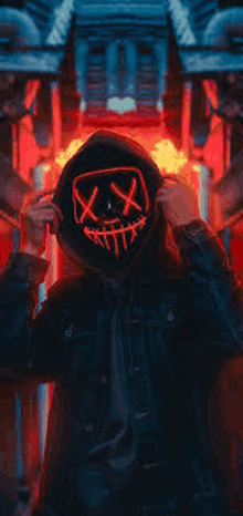 a man wearing a glow in the dark mask is standing in front of a fire .