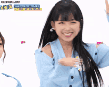 a girl in a blue sweater is smiling and looking at the camera