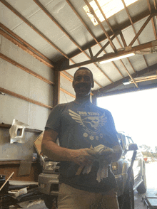 a man wearing a shirt that says sheet dog stands in a garage