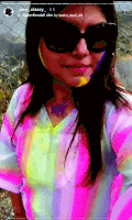 a woman wearing sunglasses and a rainbow colored shirt is taking a picture