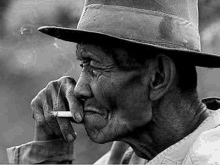 a man in a hat is smoking a cigarette .