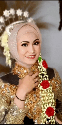 a woman wearing a hijab and a gold dress is smiling