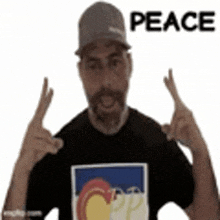 a man wearing a hat and a black shirt is making a peace sign with his hands .