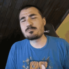 a man with a beard and mustache is wearing a blue shirt that says mc