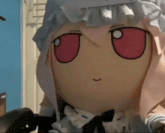 a close up of a stuffed doll with red eyes and a hat