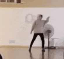 a man is dancing in a room with a fan .