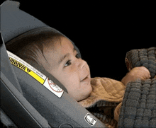 a baby is laying in a car seat with a warning label on it