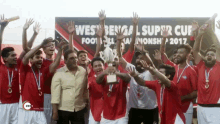 a group of soccer players holding up a trophy in front of a banner that says west bengal super cup