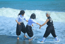 three people standing on a beach holding hands with one wearing a shirt that says ' ao no exorcist ' on it