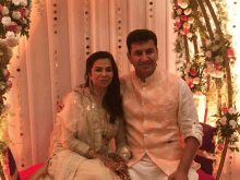 a man and a woman pose for a picture in front of a flower arrangement