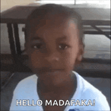 a young boy is sitting in front of a table with the words `` hello madafaka '' written on the bottom .