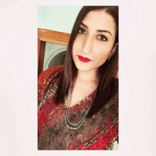 a woman wearing a necklace and red lipstick poses for a selfie