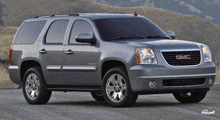 a silver gmc yukon is parked on a road