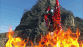 a person in a red costume is standing in front of a mountain with flames