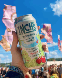 a can of inch 's medium apple cider is held in someone 's hand