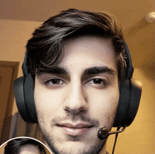 a young man wearing headphones and a microphone looks at the camera