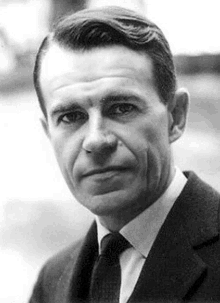 a black and white photo of a man wearing a suit and tie .