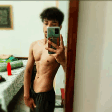 a shirtless man taking a picture of himself in the mirror