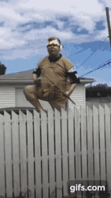 a statue of a man sitting on top of a white picket fence with gifs.com at the bottom of the screen