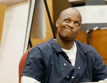 a man in a blue jacket is sitting at a desk and looking up