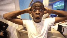 a man with a surprised look on his face holds his hands to his ears