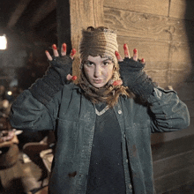 a woman wearing a hat and gloves has red paint on her hands