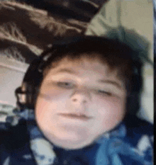 a young boy wearing headphones is sitting on a bed .