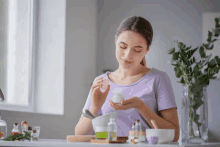 a woman in a purple shirt is preparing a cream