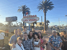 a group of people standing in front of a sign that says welcome to fabulous las vegas