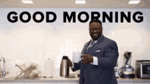 a man in a suit is holding a cup of coffee in front of a sign that says `` good morning '' .