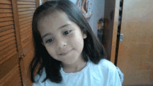 a little girl is smiling in front of a wooden closet