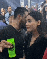 a man kissing a woman in a crowd while holding a green cup that says " beer " on it