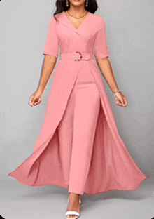 a woman is wearing a long pink dress with a belt around her waist .