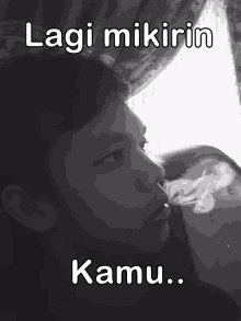 a black and white photo of a man smoking with the words lagi mikirin kamu below him