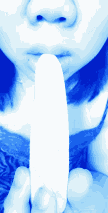 a woman in a blue shirt is holding a banana in her hand