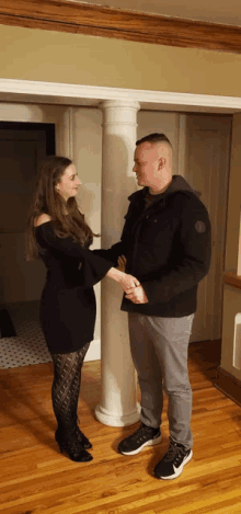 a man and a woman are holding hands in a living room