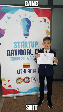 a young boy holding a certificate in front of a banner that says startup national