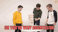 three men are playing a game of jenga and one of them is pointing at a stack of wooden blocks .