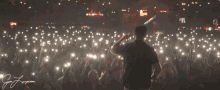 a man stands in front of a crowd at a concert with a sign that says coffee shop in the background