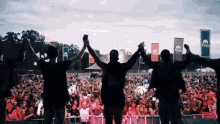 a group of people holding hands in front of a crowd at a music festival with a banner that says mountain